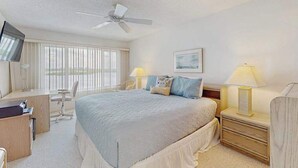 A hotel room with a bed, desk, chair, nightstands, lamps, and a ceiling fan. - Waterfront condo with pool, internet & breathtaking balcony views (Sarasota)