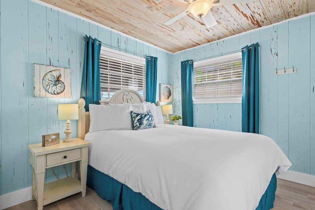 A bedroom with a bed, nightstand, and curtains.