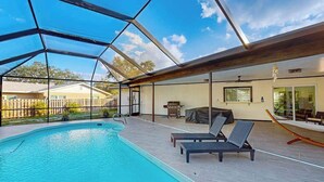 A swimming pool with a glass ceiling, lounge chairs, and a view of the backyard. - Beautiful home with private pool and space for the whole family (Sarasota)