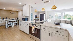 A modern kitchen with white cabinets, a built-in oven, and pendant lighting. - Beautiful home with private pool and space for the whole family (Sarasota)