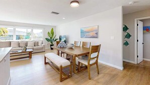 A modern living room with a dining table, sofa, and a large window. - Beautiful home with private pool and space for the whole family (Sarasota)