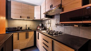 A modern kitchen with wooden cabinets, a black countertop, a stove, and a coffee maker. - Accommodation in Condesa with a balcony, within walking distance of Roma (Ciudad de México)
