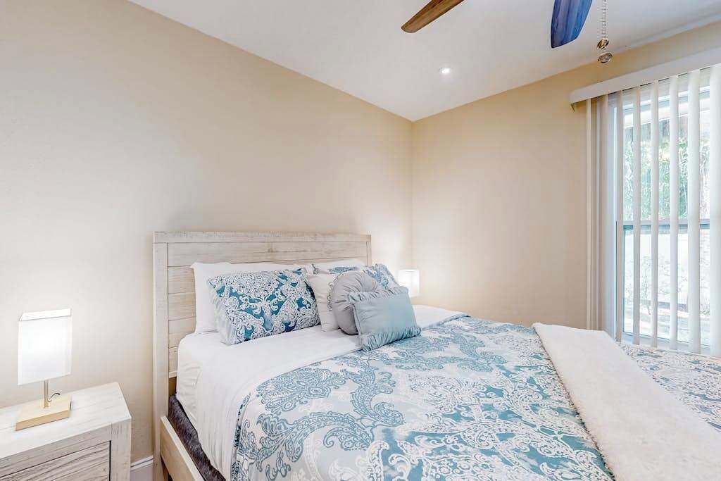 Een slaapkamer met een bed, nachtkastjes en een raam met zonwering.