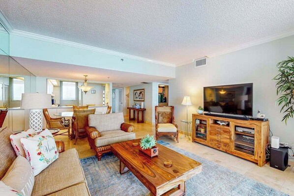 A spacious living room with a large flat-screen TV, wooden coffee table, and comfortable seating. - Oceanfront condo with shared pool, ocean view, WiFi, & washer-dryer (Longboat Key)