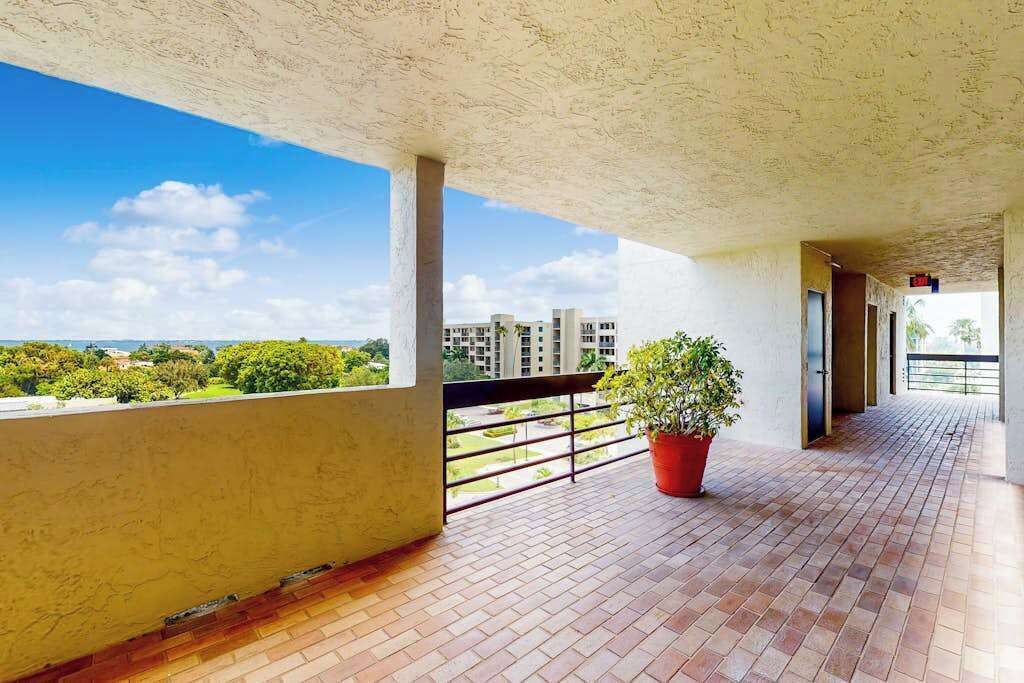 Un balcón techado con vistas a edificios y vegetación.