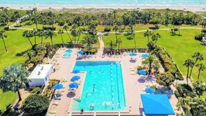 Ein Poolbereich mit mehreren Schwimmbecken, Liegestühlen und Sonnenschirmen.