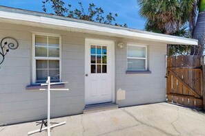 A single-story house with a white door, two windows with shutters, a small porch, and a wooden fence. - Cozy retreat, steps away from Gulf and beaches, dog friendly, AC (Holmes Beach)