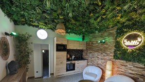 A modern interior with a kitchen, seating area, and a wall with greenery and a neon sign.