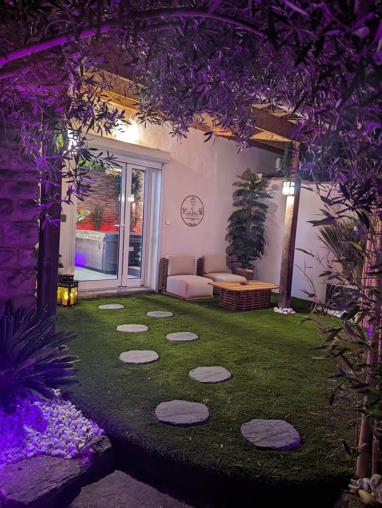 Um jardim com um sofá, uma mesa de madeira e pedras para caminhar.