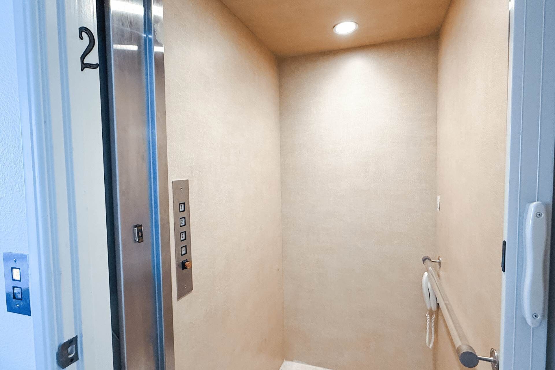 Un área de ducha pequeña y cerrada con un panel de control, una puerta con un número y una luz en el techo.