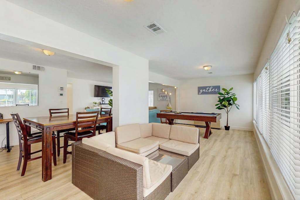 A spacious living area with a dining table, sofa, and a pool table.