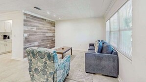 A modern living room with a sofa, armchair, and coffee table. - Cozy home with washer and dryer, internet, and prime location (Bradenton)