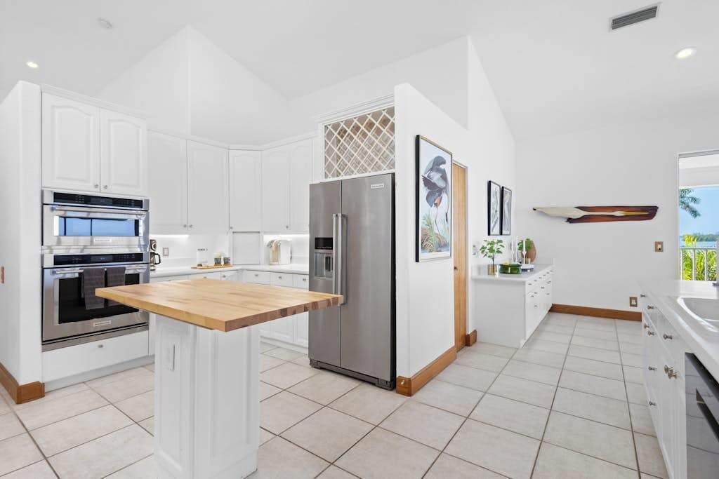 A modern kitchen with white cabinetry, stainless steel appliances, and a central island.