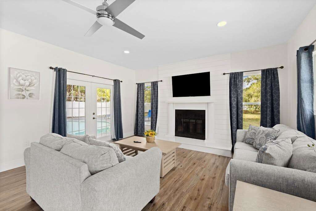 A modern living room with a fireplace, grey sofas, a coffee table, and a ceiling fan.