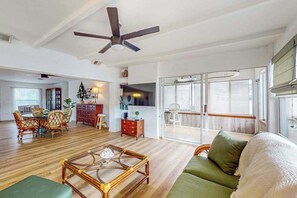 A spacious living area with a dining set, a green sofa, a wooden coffee table, and a ceiling fan. - Waterfront Home with  Pool, Private Washer & Dryer, and Gazebo (Bradenton)