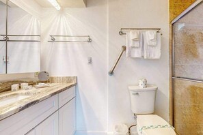 A bathroom with a marble countertop, a toilet, a shower area, and a handrail for accessibility. - Waterfront Home with  Pool, Private Washer & Dryer, and Gazebo (Bradenton)