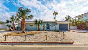 A two-story house with a garage, palm trees, and a gravel driveway. - Waterfront Home with  Pool, Private Washer & Dryer, and Gazebo (Bradenton)
