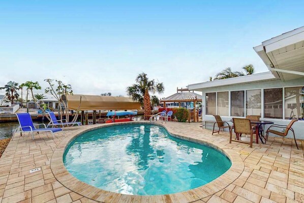 A pool area with lounge chairs, a covered seating area, and a view of the water. - Waterfront Home with  Pool, Private Washer & Dryer, and Gazebo (Bradenton)