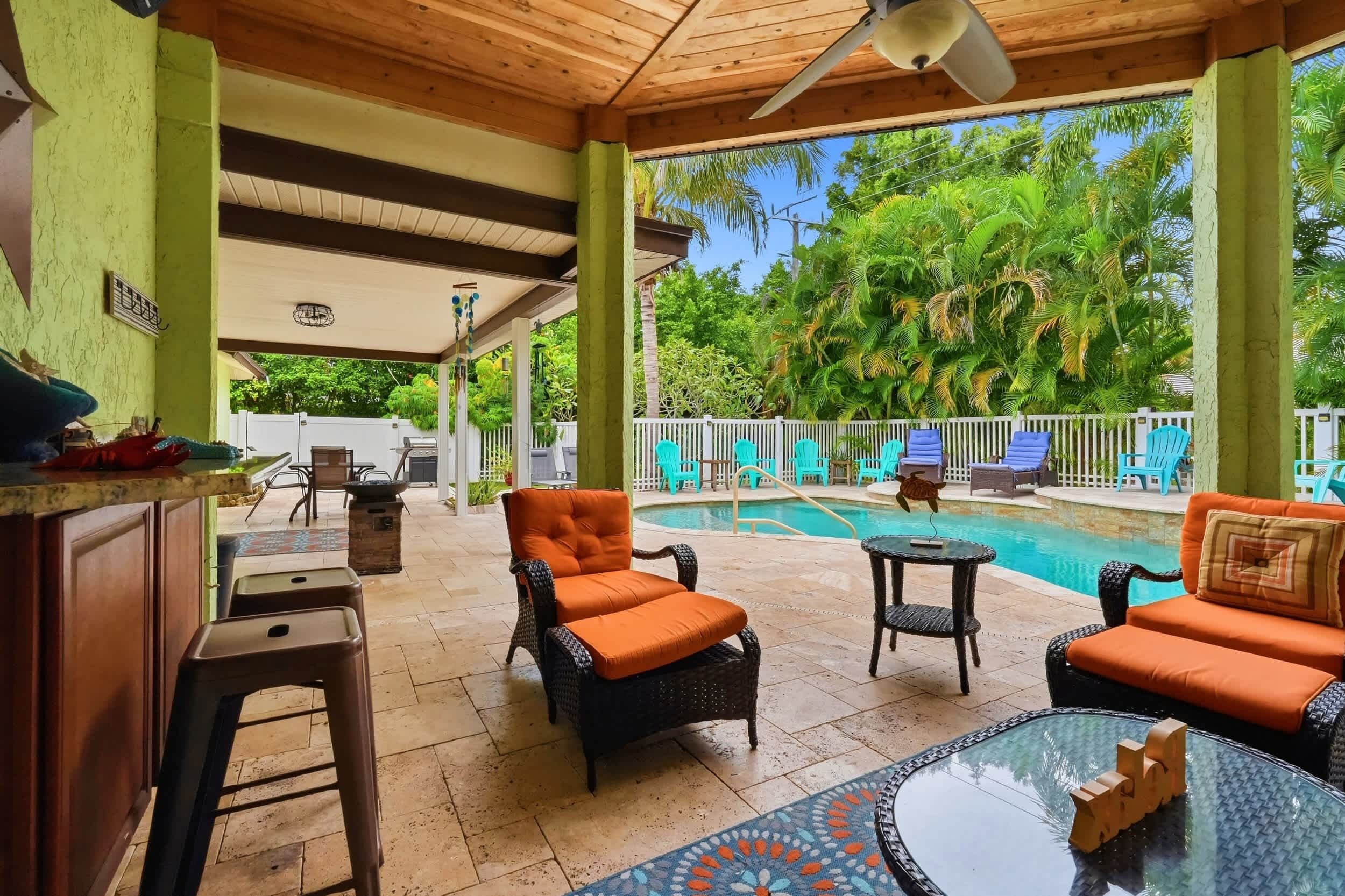 A covered outdoor area with a pool, lounge chairs, and a bar area.