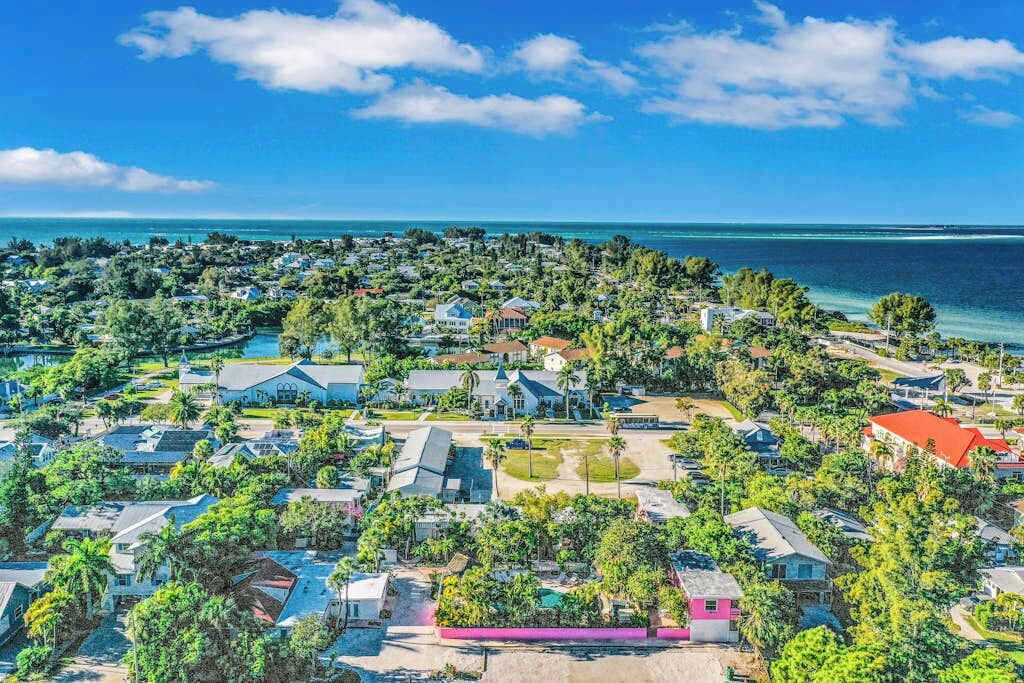 A coastal residential area with houses, trees, and a clear view of the ocean.
