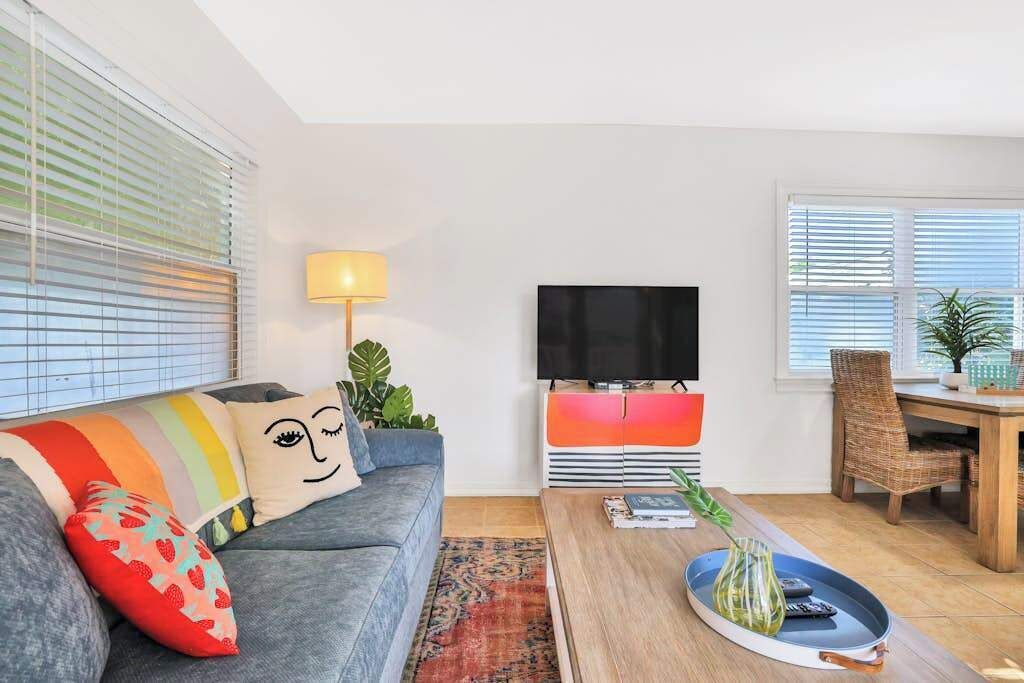 A living room with a sofa, TV, dining table, and a plant.