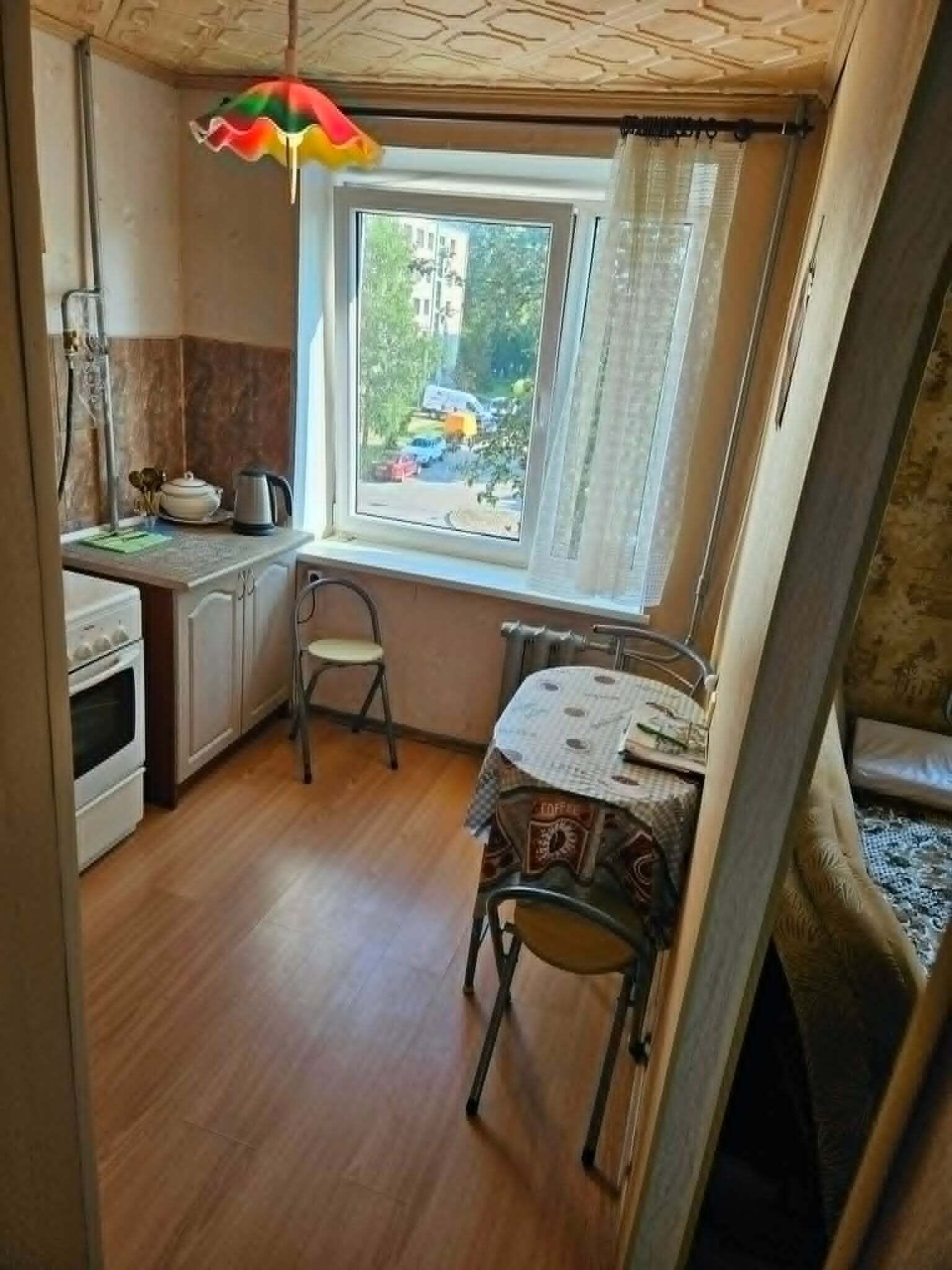 A compact kitchen with a window, a table, and a chair.