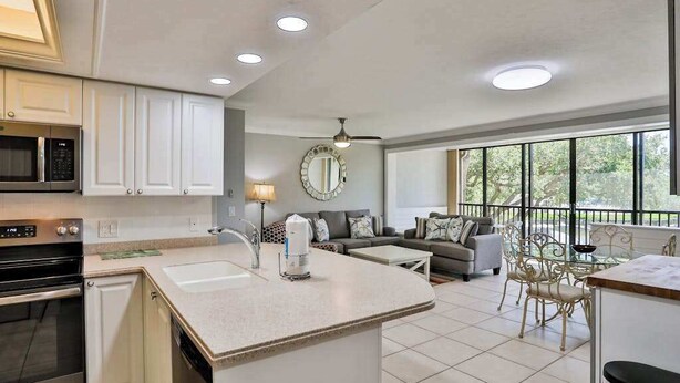 Een moderne keuken met inbouwapparatuur, een centraal eiland en een eethoek met een glazen tafel en stoelen.