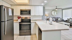 Een moderne keuken met een centraal eiland, een inbouwoven, magnetron en koelkast.