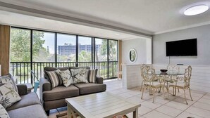 Een ruime woonkamer met een bank, salontafel en een eettafel met stoelen.