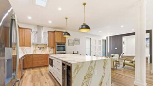 Une cuisine moderne avec des plans de travail en marbre, des armoires en bois et des luminaires suspendus.