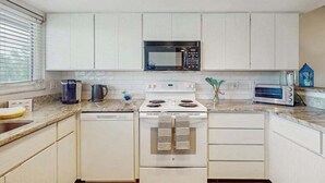 Une cuisine moderne avec des meubles blancs, un four à micro-ondes, une cuisinière, un lave-vaisselle et un grille-pain.