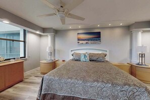 Een slaapkamer met een groot bed, een plafondventilator, een schilderij en een raam.