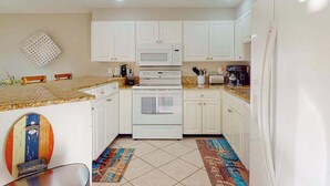 A compact kitchen with white cabinets, a microwave, stove, and a coffee maker. - Waterfront condo with Gulf views, pool, tennis, & deeded beach access (Longboat Key)