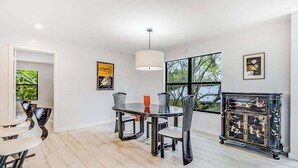 Un espace repas comprenant une table ronde, des chaises, un luminaire suspendu et des œuvres d’art accrochées aux murs.