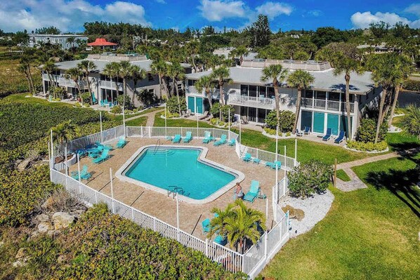 A resort with a central swimming pool, multiple guest rooms, and a well-maintained lawn. - Beachfront Condo with a Beautiful, Renovated Kitchen, Shared Pool, & Tennis (Longboat Key)