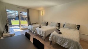 Ett hotellrum med två sängar, ett bord och en skjutdörr i glas som leder ut till en uteplats.
