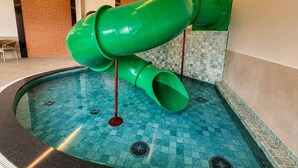 A pool with a green slide and a red pole. - Castelos do Vale by Livá OFICIAL (Vale dos Vinhedos)