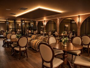 A restaurant with wooden tables and chairs, brick walls, and barrel decorations.