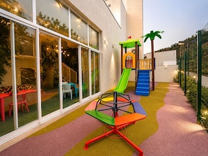 Un área de juegos infantiles con un tobogán, una estructura para escalar y un asiento giratorio.