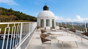 Una terraza en la azotea con una estructura en forma de cúpula blanca, mobiliario de mimbre y barandilla blanca.