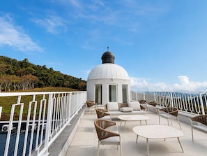 A rooftop terrace with a white dome structure, wicker furniture, and a white railing.
