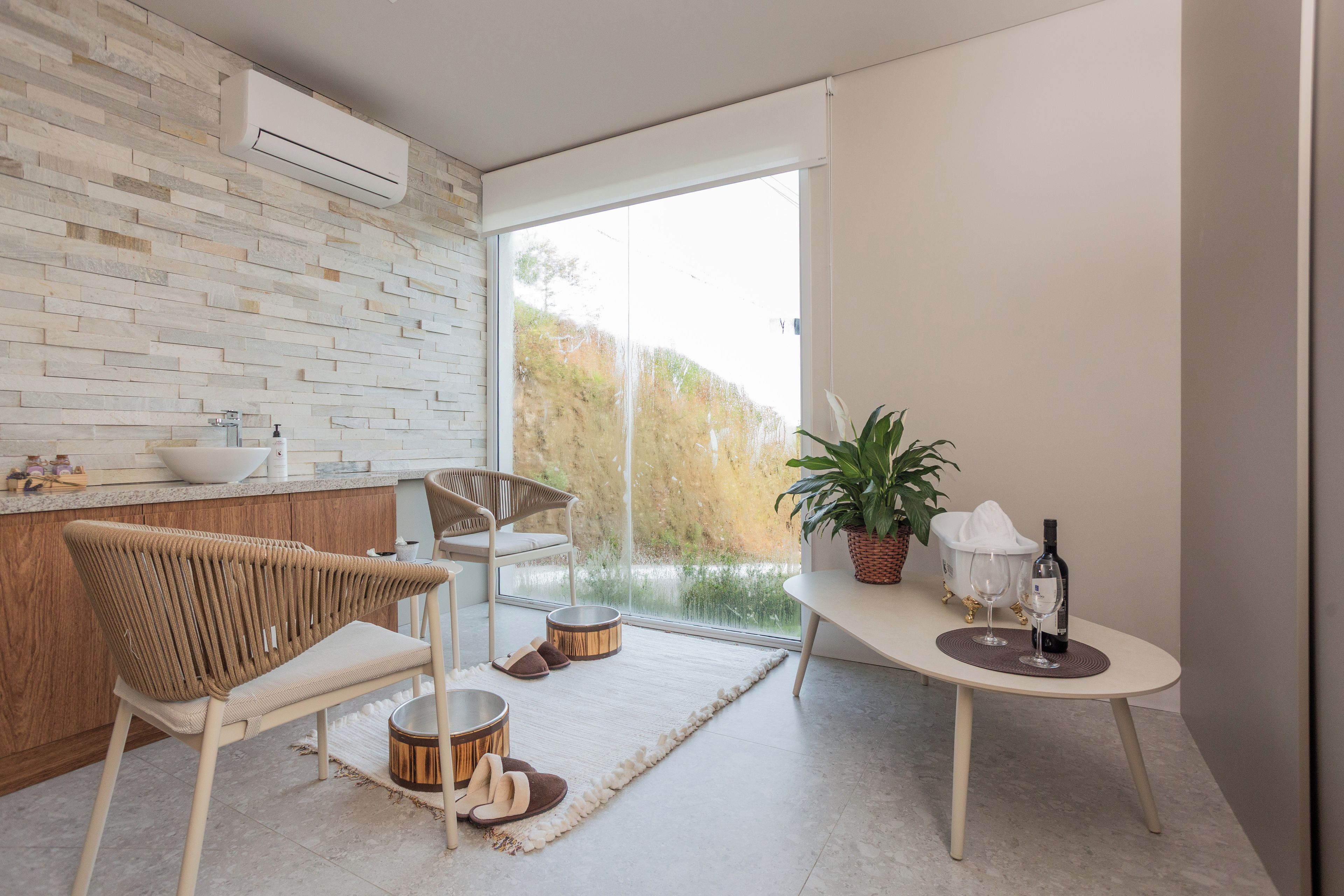 Cozinha moderna com painel de pedra, área de jantar com mesa redonda e vista para o exterior.