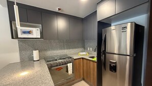 A modern kitchen with a built-in microwave, stove, and stainless steel refrigerator. - Duo 24 Apartment, Tower A (Zapopan)