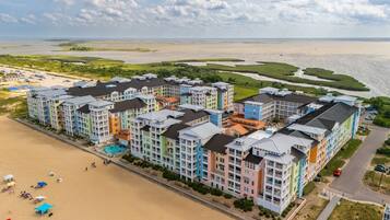 Un hotel de varios pisos con balcones, piscina y zona de playa.