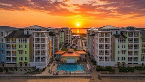 Ein Resort mit mehreren Gebäuden, einem Schwimmbad und Blick auf einen Sonnenuntergang.