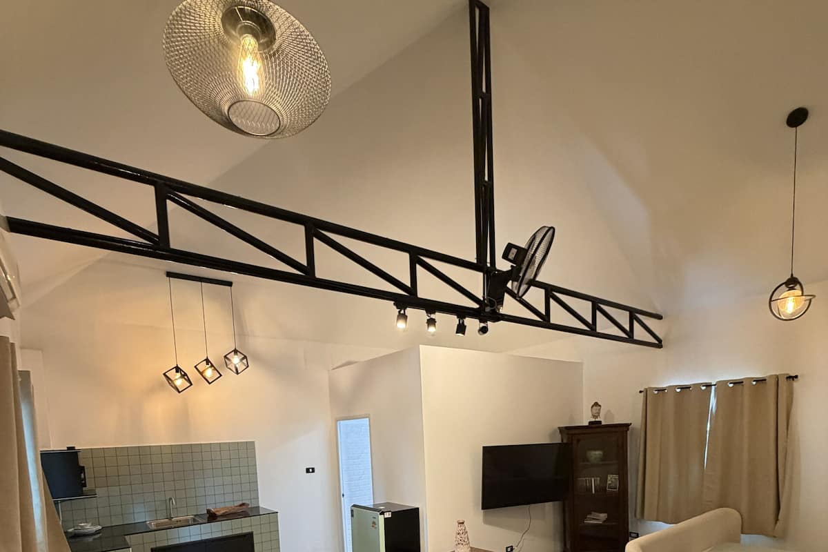 Un espacio habitable moderno con sofá, mesa de centro, zona de cocina y televisor.