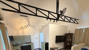 Una sala de estar moderna con un sofá, una mesa de centro, un televisor de pantalla plana y una cocina al fondo.