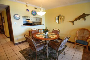 A dining area with a round table, wicker chairs, a chandelier, and a fish decoration on the wall. - Land's End Resort - Relaxing Oceanfront Getaway with Private Balcony & Resort Am (Myrtle Beach)