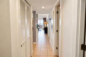 A hallway with a tiled floor, white walls, and doors on both sides. - Land's End Resort - Oceanfront Views & Resort Amenities (Myrtle Beach)