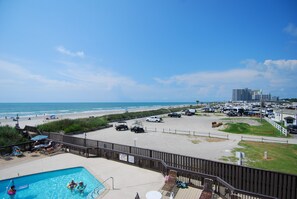 A beach view with a swimming pool, beach chairs, and a parking area. - Land's End Resort - Oceanfront Views & Resort Amenities (Myrtle Beach)